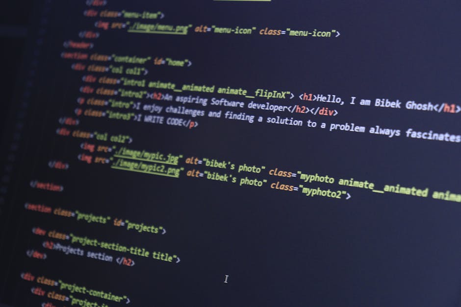 A photograph displays a close-up of a computer screen showing lines of HTML code with colorful syntax highlighting, including tags for headings, images, and descriptive classes. The code appears on a